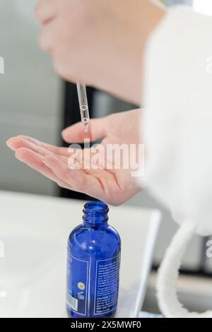 Close-up of woman dropping serum on hand Stock Photo