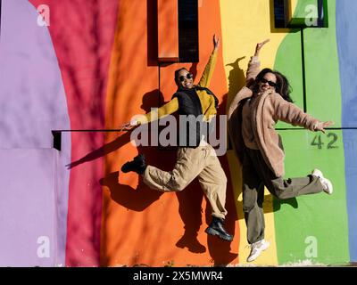 Two young women jumping in front of colorful graffiti wall Stock Photo