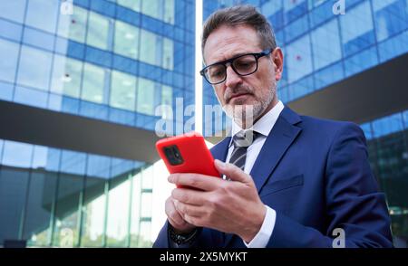 Caucasian mature businessman outside financial district using cellphone. Stock Photo