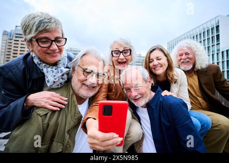 Group happy senior people using mobile phone together outdoor. Elderly friends and smiling Stock Photo