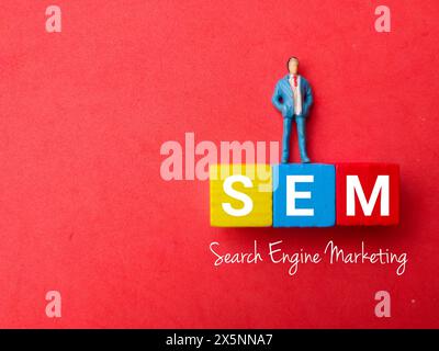 Top view miniature people with text SEM (Search Engine Marketing) on red background Stock Photo