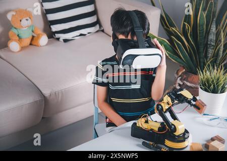 Asian kid boy using VR glasses on robotic arm in workshop Stock Photo