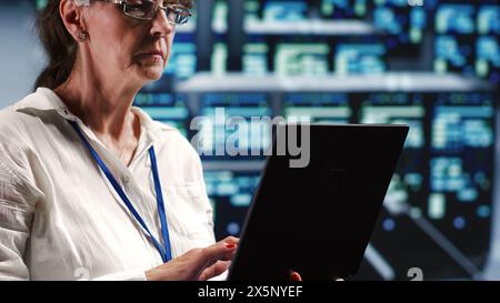 Senior technician in server room equipped to handle modern computing requirements, doing regular upgrades to components, increasing processing power and storage capacity to prevent flaws Stock Photo