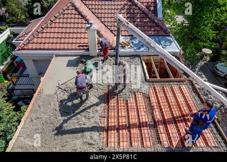 Construction workers pour concrete mix on a steel reinforced roof slab. Stock Photo