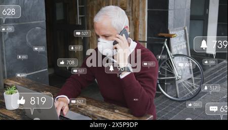 A middle-aged Caucasian chef/restaurant owner is talking on phone and using laptop Stock Photo