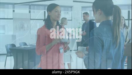 Diverse team of coworkers holding coffee cups and talking Stock Photo