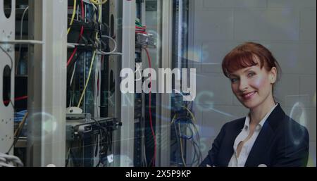 Cyber security data processing over portrait of caucasian female engineer smiling at server room Stock Photo