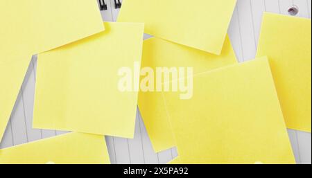 Multiple yellow sticky notes lying on white wooden surface Stock Photo