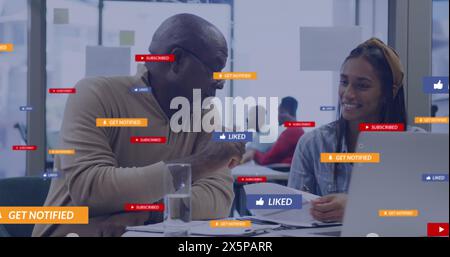 A group of diverse business colleagues talking and using laptops in an office Stock Photo
