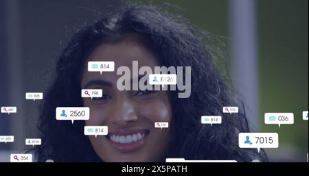 Image of icon and changing numbers in notification bars, portrait of smiling biracial woman Stock Photo