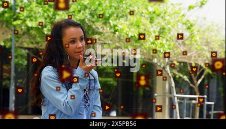 Image of icons connected with lines over biracial woman talking on speaker of cellphone Stock Photo