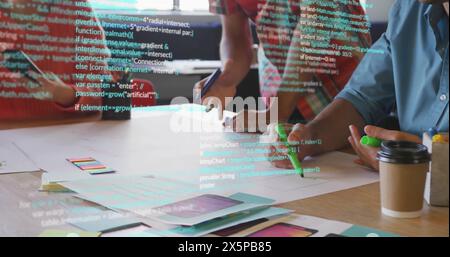Image of multicolored computer language over diverse coworkers discussing blueprint Stock Photo
