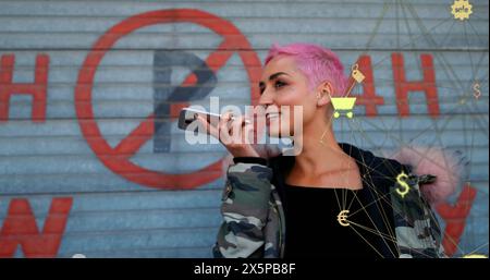 Image of connected icons globe over biracial woman talking on speaker of smartphone Stock Photo