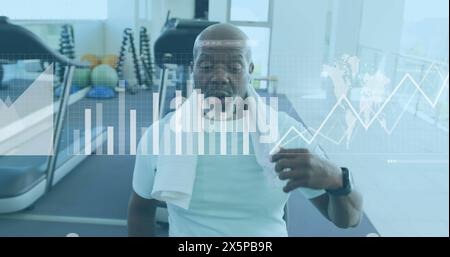 Image of graphs, loading bars, map, tired african american man wiping head with towel in gym Stock Photo