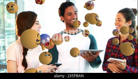 Two Caucasian females and one biracial male, laughing, sharing content on devices Stock Photo