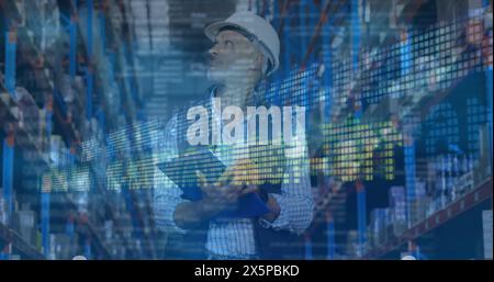 Caucasian middle-aged man wearing hard hat, holding clipboard in warehouse Stock Photo