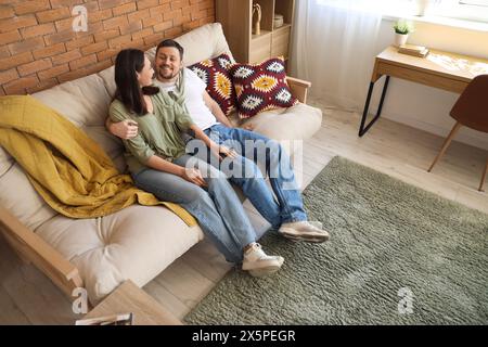 Young couple hugging on sofa with green carpet at home Stock Photo