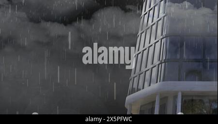 Rain falling and thunderstorm over tall building against dark clouds in the sky Stock Photo