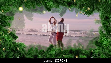 Image of fir tree frame over happy diverse senior couple danging on beach Stock Photo