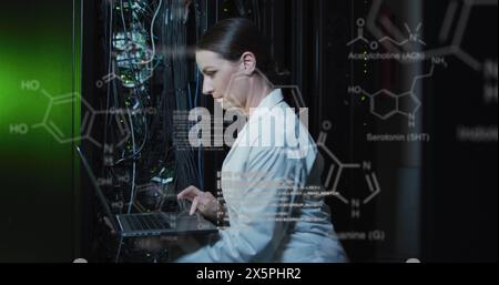 A caucasian female it technician is using a laptop to check a computer server Stock Photo
