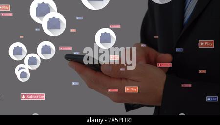 Image of social media icons floating over mid section of a businessman using smartphone Stock Photo