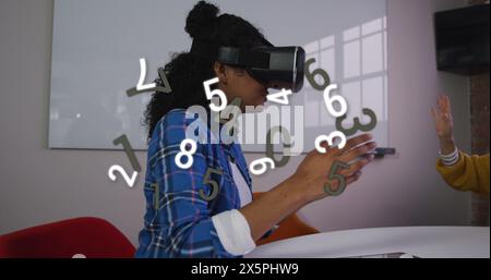 Image of changing numbers over african american woman using vr headset Stock Photo