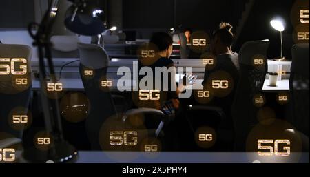 Image of multiple 5g texts over rear view of diverse coworkers discussing reports in office Stock Photo