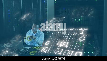 Image of binary codes, african american man feeding cable details in laptop at server room Stock Photo