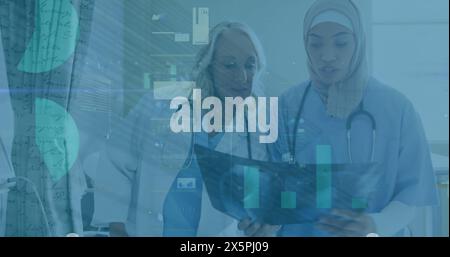 Image of data processing over two diverse female doctors discussing over x-ray at hospital Stock Photo