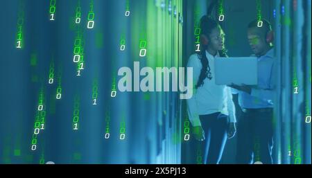 Image of falling binary codes, african american coworkers discussing in server room Stock Photo