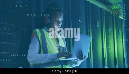 Image of computer language, african american female engineer using laptop in server room Stock Photo
