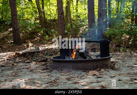 A small blaze dances in a fire pit on a cool fall day in the beautiful state of Arkansas. Slightly defocused trees in the backround portray the serene Stock Photo