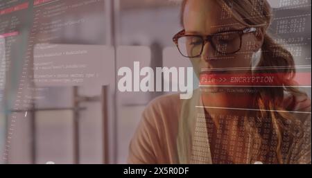 Caucasian female, wearing glasses, focusing on coding on computer Stock Photo