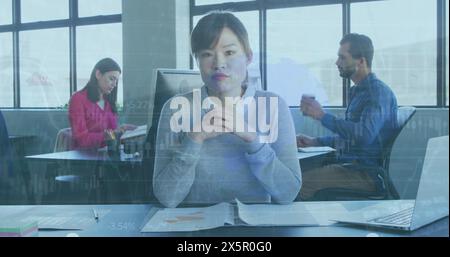 Diverse colleagues focusing on work, Asian woman in front Stock Photo