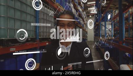 Image of loading bars and graphs over smiling biracial female manager in factory Stock Photo