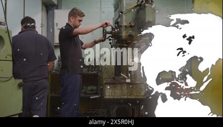 Image of globe rotating over diverse man walking towards coworker using machinery in garage Stock Photo