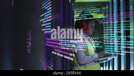 Image of data processing on african american female engineer using laptop working at server room Stock Photo