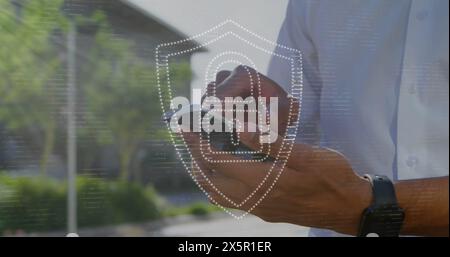 Image of padlock in shield over midsection of caucasian man scrolling on smartphone Stock Photo