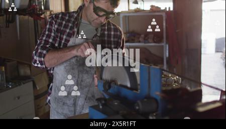 Image of people icons moving up over caucasian male mechanic using machinery in workshop Stock Photo