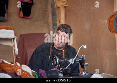 Baiona, Pontevedra, Galicia, Spain; March, 04,2023; an artisan shoemaker sewing and with glasses at the Arribada festival Stock Photo