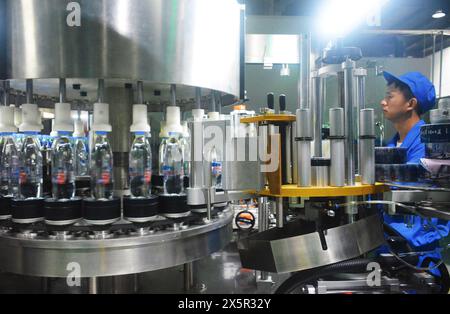 ANQING, CHINA - MAY 11, 2024 - A worker is working on a bottled water production line at a workshop of a beverage company in Anqing city, East China's Stock Photo