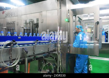 ANQING, CHINA - MAY 11, 2024 - A worker is working on a bottled water production line at a workshop of a beverage company in Anqing city, East China's Stock Photo