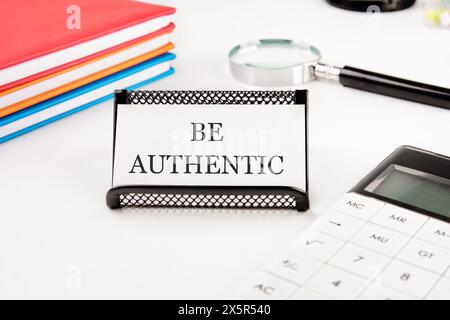 Text Be Authentic on a business card in a composition with a calculator, notebooks and a magnifying glass Stock Photo