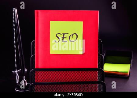 SEO business, SEO concept. Search engine optimization text on a yellow sticker on a red notepad in front of a black background. A place to copy Stock Photo