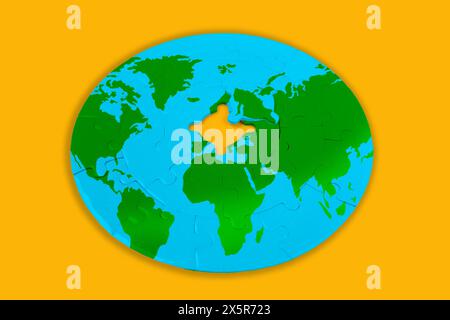 Circular puzzle shaped like a globe with the final central piece to be set in place. Exploration and education related concept. Stock Photo