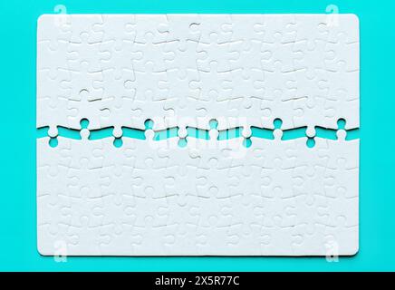 Close-up of a blank rectangular jigsaw puzzle split in half and isolated on light blue background. Stock Photo
