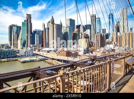 From the footpath over the Brooklyn Bridge, you can see the skyline of downtown Manhattan, New York City, through a tangle of tensioning wires Stock Photo