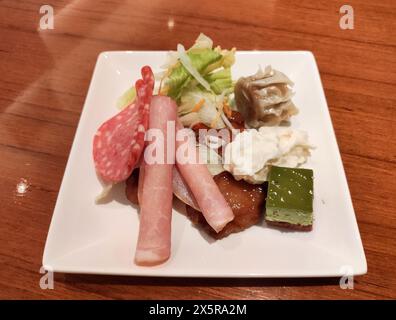 different kind of snacks on the white plate on the wood table Stock Photo