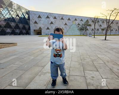 Giza, Egypt, April 13 2024: A young tourist child taking a selfie picture at The Grand Egyptian Museum, Giza Museum, Egypt's gift to the world, the la Stock Photo
