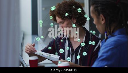 Image of globe of digital icons over two diverse male office colleagues discussing over document Stock Photo
